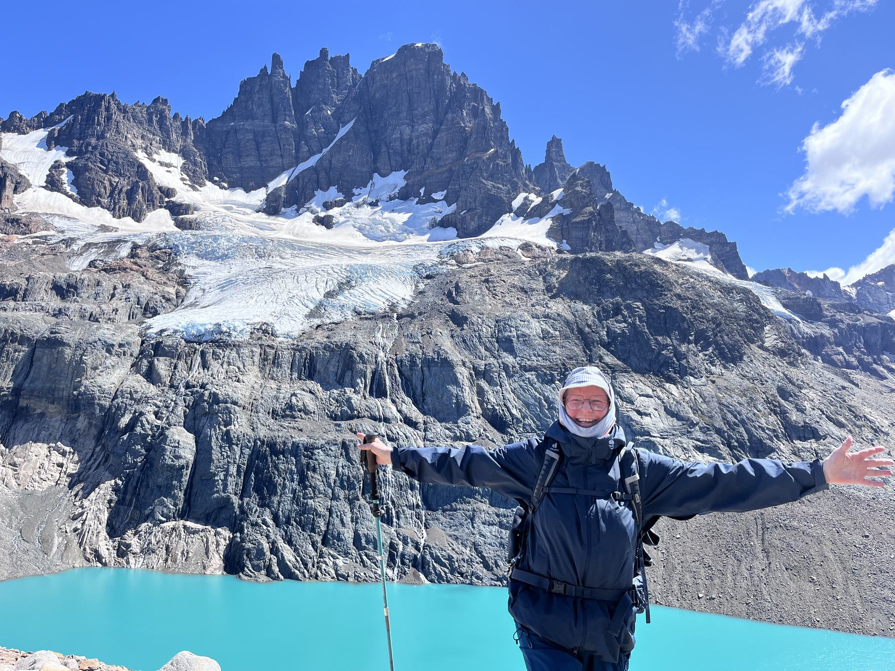 Excursionista celebrando frente a la laguna turquesa y el glaciar colgante de Cerro Castillo
